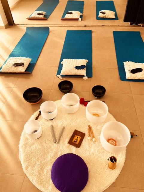 Mats, cushions and eye masks laid out around crystal bowls for a group sound bath