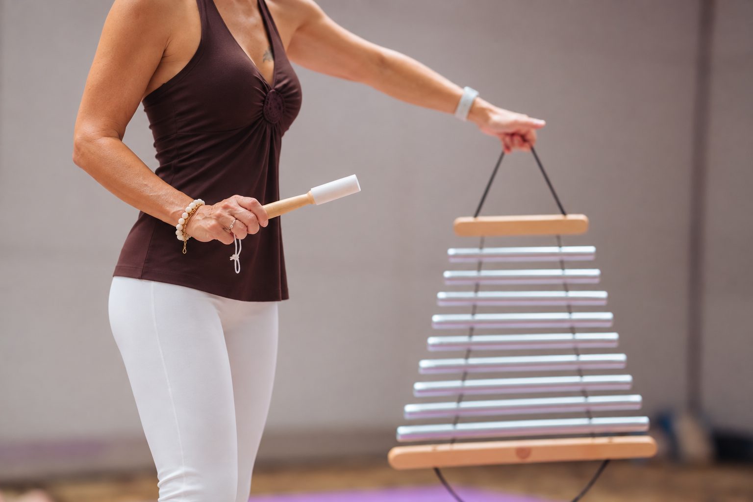 Laurence holding a set of chimes, arm extended, in a studio