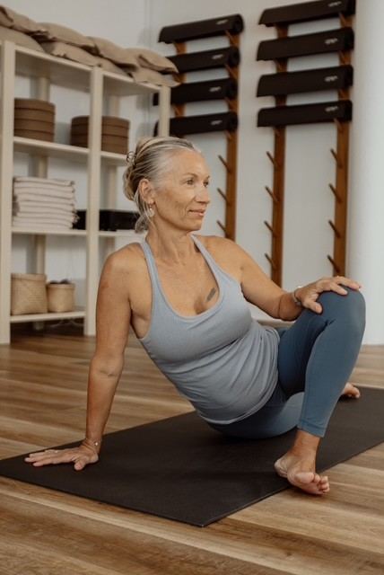 Laurence in a seated twist on her mat, smiling