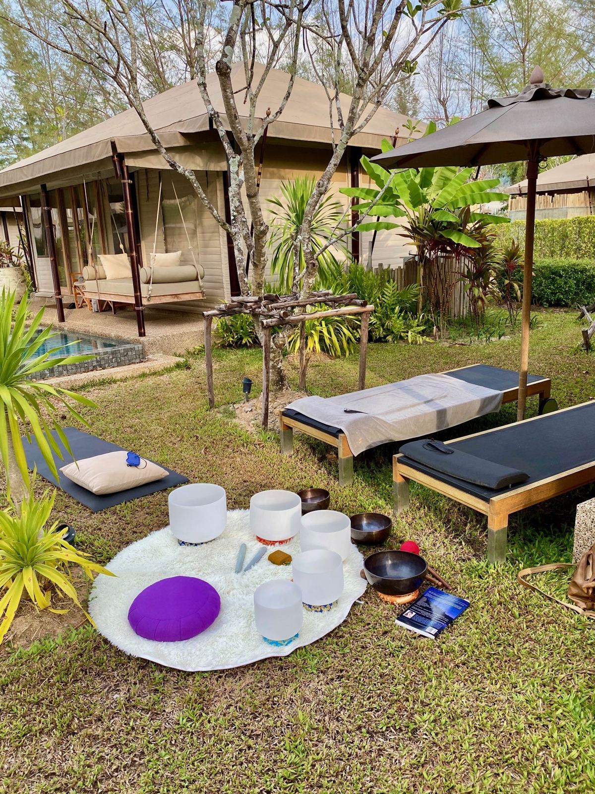 Crystal bowls and a meditation cushion set up in a villa garden